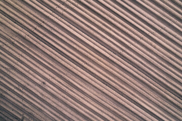 Aerial view of furrows on brown raw plowed field