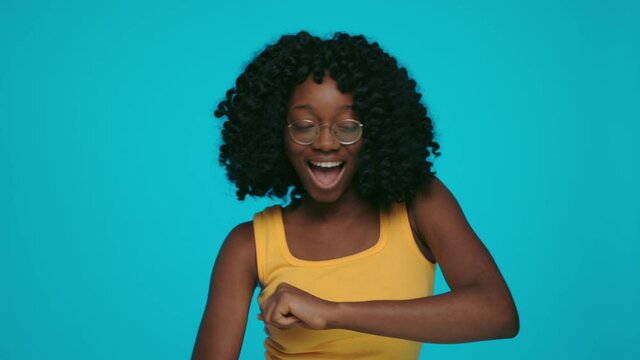 African woman dancing actively over yellow background