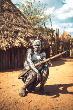 Man with painted body holding a shotgun in Karo tribe village. Omo Valley, Ethiopia