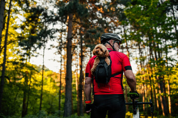 Man and dog in backpack on bike tour in forest
