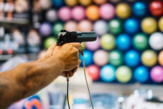 Unrecognizable man shooting a gun to the balloons wall