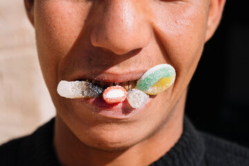 Ethnic person with bad teeth eating candy