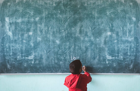 Anonymous black boy writing on chalkboard