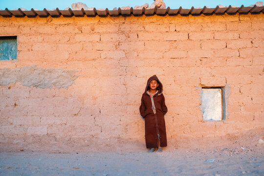 Ethnic kid standing near shed