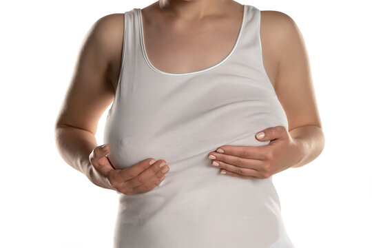 A woman in white shirt holds her univen big breasts