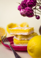 side view of juicy yellow lemon cakes on a red plate, stack of citrus cookies with lemon filling lying one on top of another