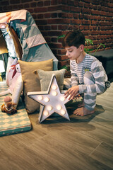 Male teen placing a star lamp helping preparing a slumber party © David Pereiras