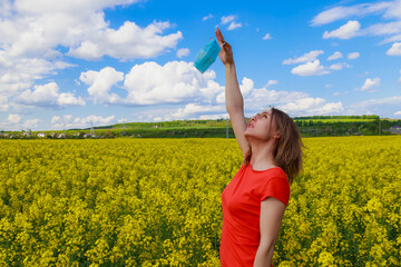 Young pretty woman in a colored dress on Lightning cheerful yellow background blooming rapeseed...