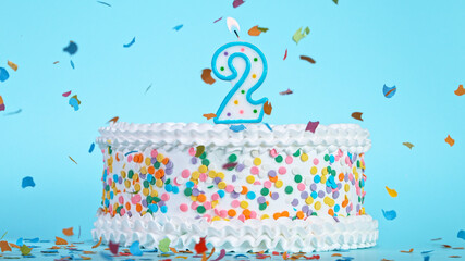 Colorful tasty birthday cake with candles shaped like the number 2. Pastel blue background.