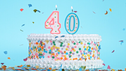 Colorful tasty birthday cake with candles shaped like the number 40. Pastel blue background.