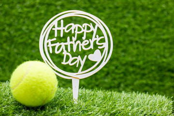 Tennis ball for Happy Father's Day are on green grass
