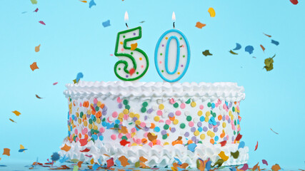 Colorful tasty birthday cake with candles shaped like the number 50. Pastel blue background.