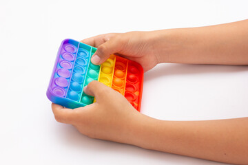 Anonymous child with colorful poppit game. Close up shot of kid hand playing with colorful pop It fidget toy.