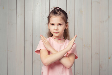 little girl show cross stop gesture, say no, block and taboo gesture, standing displeased and...