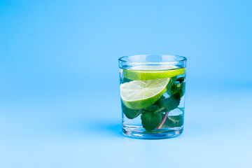 Fresh water in glass with lime and mint on aqua blue background. Part of set.