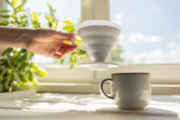 A female's hand removes a funnel with a filter from the cup. Alternative mothod of coffee brewing....