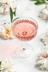 Delicious Rose sweet wine in glass with Peony Flowers on white background, Summer drink for party, wine shop or wine tasting concept. vertical image. top view