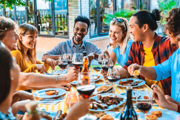 Group of friends having fun at bbq dinner outdoor in garden restaurant - Multiracial people eating...
