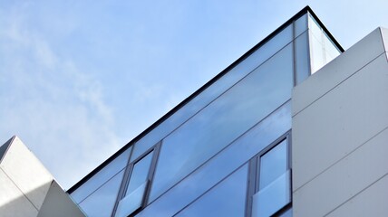 Abstract closeup of the glass-clad facade of a modern building covered in reflective plate glass. Architecture abstract background. Glass wall and facade detail.