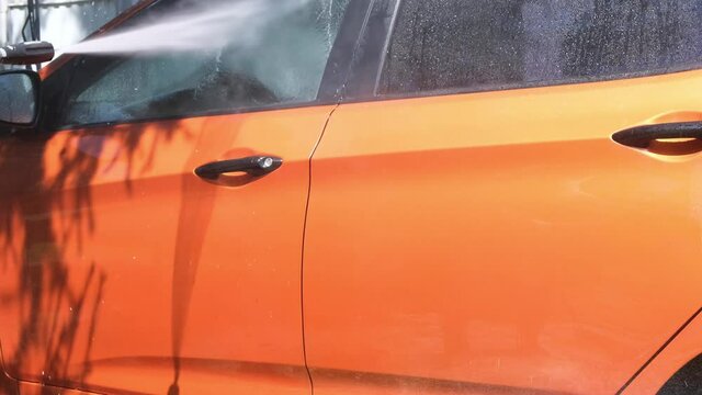 Manual car wash with pressurized water in car wash outside in summer.