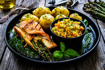 Stuffed turkey breast with mozzarella and asparagus,    boiled potatoes and fresh vegetable salad on wooden background
