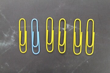 Yellow paper clips are stacked and one click of another blue color