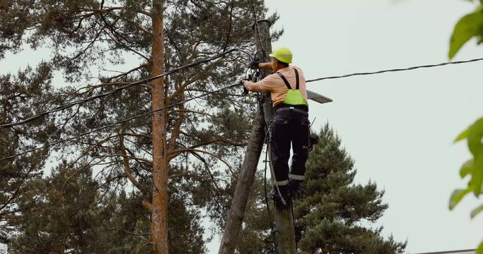 electrical lineman connecting wires high on electric pole. powerline maintenance and repair