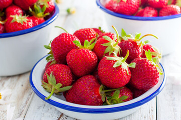 Fresh strawberries in an enamel bowl on a wooden table, selective focus