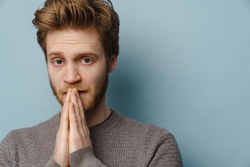 White ginger man looking at camera while holding palms together