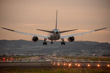 Fototapeta na wymiar 夕陽を背景に着陸する飛行機のイメージ