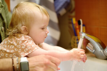 Cute baby and dad washing their hands with soap in bathroom together. Hygiene for little child. Father's involvement in raising children. Happy parenthood.
