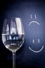 Half-full or half-empty glass of water, with an happy smiley and unhappy smiley, showing optimism...