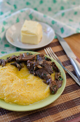 Corn porridge, fried mushrooms with onions and butter in plates on the table.