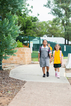 Two happy school friends walking to school together