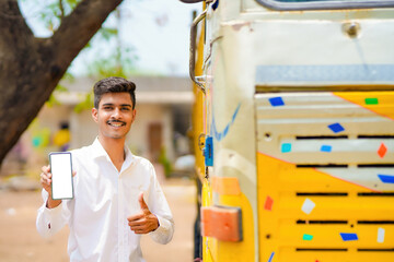 Young indian businessman with his freight forward lorry or truck and showing smartphone.