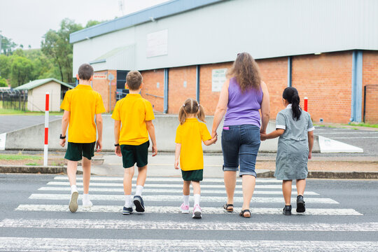 School mum walking across pedestrian crossing with kids on an excursion