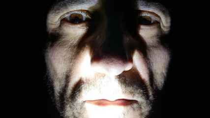 Scary ugly man face marked by wrinkles close up at night with light and shadow, horror character with crazy eyes and red lips