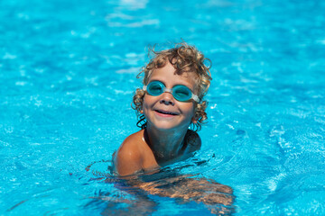 Fototapeta na wymiar Curly boy in the pool with glasses