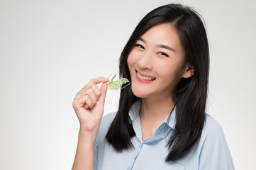 Asian woman holding orthodontic retainers.Teeth retaining tools after braces ... - obrazy, fototapety, plakaty