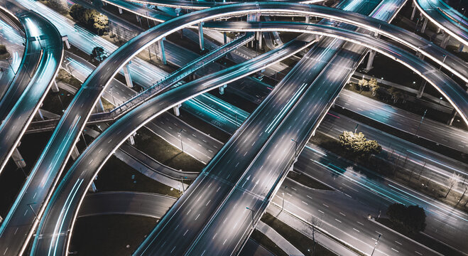 Night long exposure illumination of elevated multilevel traffic junction. Modern development of backlighted roads and current new infrastructure in China, Chengdu. Aerial drone point of view.