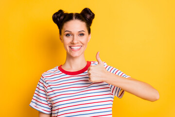 Photo of sweet shiny young lady wear striped t-shirt smiling showing thumb up isolated yellow color background