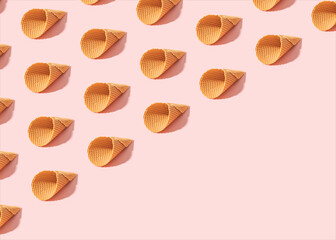 Minimal summer pattern made of empty ice cream cones on sunny pink background.  Diagonal copy space.