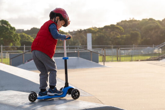 a kid riding his scooter on a ramp at a skate park