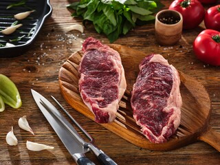 Top view of two juicy raw meat steak on a wooden cutting board. Beefsteak on kitchen preparation table