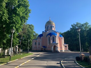 Old Orthodox Church in summer on the background of the graveyard, road and trees
