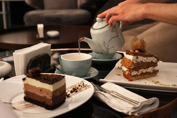tea ceremony in a cafe. man pours tea from a teapot into a cup. desserts cakes on the table with tea