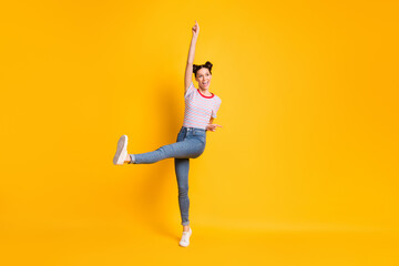 Photo of pretty shiny young girl dressed striped t-shirt pointing empty space dancing isolated yellow color background