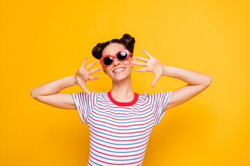 Photo of funny adorable young girl dressed striped t-shirt dark glasses dancing showing arms isolated yellow color background