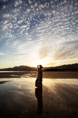 Fototapeta premium Beautiful woman dancing by the sea at sunset