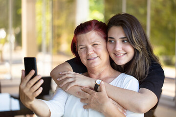 mother and daughter selfie with mobile smart phone. Happy family online photo sharing for social media. fun People parents and technology lifestyle concept.
